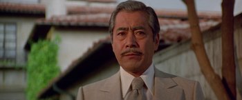 Movie still from “Winter Kills” (1979), directed by William Richert – An older man wearing a suit and tie; Close Up shot, Low angle