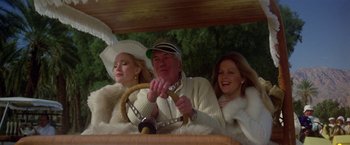 Movie still from “Winter Kills” (1979), directed by William Richert – A man and two women are driving in a car; Medium shot, Low angle