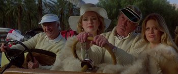 Movie still from “Winter Kills” (1979), directed by William Richert – A woman wearing a white hat and holding a steering wheel; Medium shot, Low angle