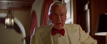 Movie still from “Winter Kills” (1979), directed by William Richert – An older man wearing a white suit and a red bow tie; Close Up shot, Low angle