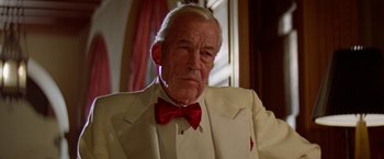 Movie still from “Winter Kills” (1979), directed by William Richert – An older man wearing a white suit and red bow tie; Close Up shot, Low angle