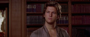 Movie still from “Winter Kills” (1979), directed by William Richert – A man in a plaid shirt in front of a book shelf; Close Up shot, Over the shoulder angle