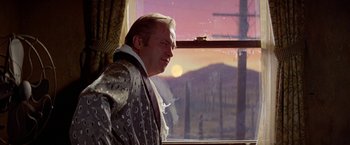 Movie still from “Winter Kills” (1979), directed by William Richert – A man standing in front of a window looking outside; Medium shot, Over the shoulder angle