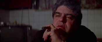 Movie still from “Winter Kills” (1979), directed by William Richert – A person smoking a cigar; Close Up shot, Low angle