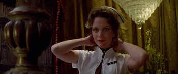 Movie still from “Winter Kills” (1979), directed by William Richert – A woman in a white shirt and a red tie; Close Up shot, Low angle