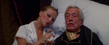 Movie still from “Winter Kills” (1979), directed by William Richert – An older man and a young woman laying in a bed; Close Up shot, Low angle