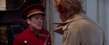 Movie still from “Winter Kills” (1979), directed by William Richert – A man in a red and gold uniform talking to another man in a brown coat; Close Up shot, Over the shoulder angle