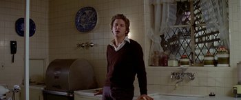 Movie still from “Winter Kills” (1979), directed by William Richert – A man standing next to a bath tub in a bathroom; Medium shot, Low angle