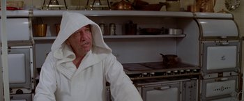 Movie still from “Winter Kills” (1979), directed by William Richert – An older man wearing a white robe in a kitchen; Close Up shot, Low angle