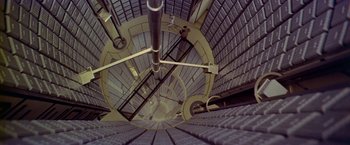 Movie still from “Winter Kills” (1979), directed by William Richert – Looking down at a spiral staircase in a building; Extreme Wide shot, Overhead angle