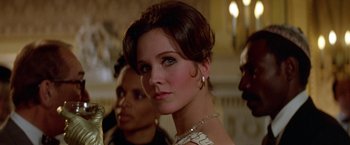 Movie still from “Winter Kills” (1979), directed by William Richert – A beautiful woman in a white dress with a necklace; Close Up shot, Low angle