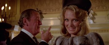 Movie still from “Winter Kills” (1979), directed by William Richert – A man and a woman are smiling and holding wine glasses; Close Up shot, Over the shoulder angle