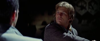 Movie still from “Winter Kills” (1979), directed by William Richert – A person sitting in a chair; Close Up shot, Low angle