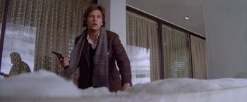 Movie still from “Winter Kills” (1979), directed by William Richert – A man standing in front of a bed in a room; Medium shot, Low angle