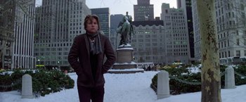 Movie still from “Winter Kills” (1979), directed by William Richert – A man standing in front of a statue in the snow; Wide shot, Low angle
