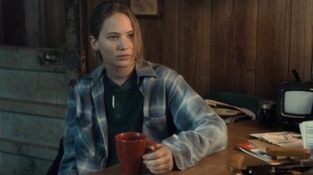 Movie still from “Winter's Bone” (2010), directed by Debra Granik – A woman sitting at a table holding a coffee mug; Medium shot, Over the shoulder angle