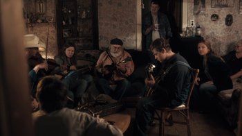 Movie still from “Winter's Bone” (2010), directed by Debra Granik – A group of people sitting around a living room playing guitars; Wide shot, High angle
