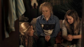 Movie still from “Winter's Bone” (2010), directed by Debra Granik – A group of people sitting on the ground; Medium shot, Over the shoulder angle