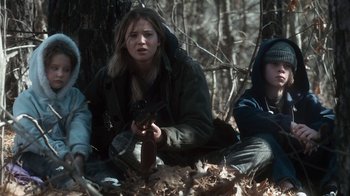 Movie still from “Winter's Bone” (2010), directed by Debra Granik – A group of people sitting on the ground in the woods; Medium shot, Over the shoulder angle