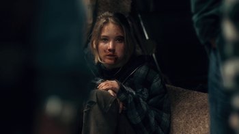 Movie still from “Winter's Bone” (2010), directed by Debra Granik – A woman sitting on top of a couch under an umbrella; Close Up shot, Over the shoulder angle