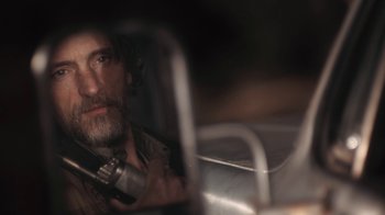 Movie still from “Winter's Bone” (2010), directed by Debra Granik – A man sitting in a chair holding a cell phone; Close Up shot, Over the shoulder angle