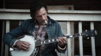 Movie still from “Winter's Bone” (2010), directed by Debra Granik – A man with a long beard playing a banjo; Close Up shot, Low angle