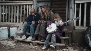 Movie still from “Winter's Bone” (2010), directed by Debra Granik – Three people sitting on steps with a guitar; Wide shot, High angle