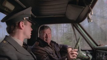 Movie still from “Wise Blood” (1979), directed by John Huston – A man and a young boy in a car looking intently at a cell phone; Medium shot, Over the shoulder angle