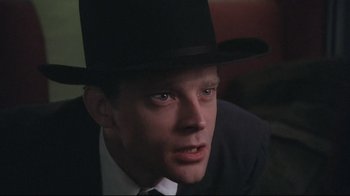 Movie still from “Wise Blood” (1979), directed by John Huston – A person wearing a suit and a hat; Close Up shot, Low angle