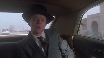 Movie still from “Wise Blood” (1979), directed by John Huston – A man in a suit and hat sitting in the back seat of a car; Close Up shot, Low angle