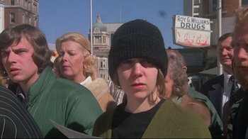 Movie still from “Wise Blood” (1979), directed by John Huston – A group of people standing next to each other on the street; Close Up shot, Low angle