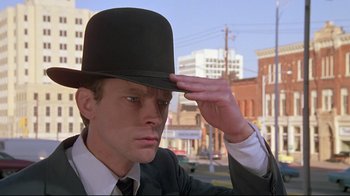 Movie still from “Wise Blood” (1979), directed by John Huston – A man in a suit and a hat is saluting; Close Up shot, Low angle
