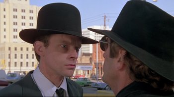 Movie still from “Wise Blood” (1979), directed by John Huston – Two men wearing hats and one is looking into the other's eyes; Close Up shot, Over the shoulder angle
