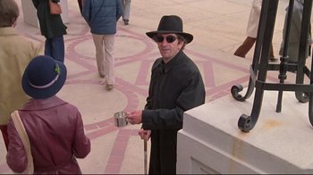 Movie still from “Wise Blood” (1979), directed by John Huston – A man in a black hat and sunglasses holding a cup; Medium shot, High angle