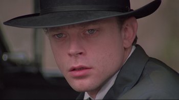 Movie still from “Wise Blood” (1979), directed by John Huston – A person wearing a suit and a hat; Close Up shot, Low angle