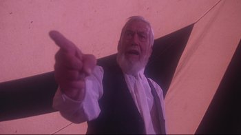 Movie still from “Wise Blood” (1979), directed by John Huston – An old man with a white beard pointing to the side; Medium shot, Low angle