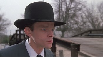 Movie still from “Wise Blood” (1979), directed by John Huston – A man wearing a black hat and a suit; Close Up shot, Low angle