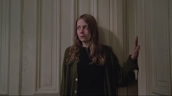 Movie still from “Wise Blood” (1979), directed by John Huston – A woman standing in front of a white wall; Medium shot, Low angle