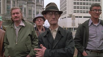 Movie still from “Wise Blood” (1979), directed by John Huston – An older man wearing a hat and glasses; Medium shot, Low angle