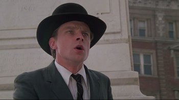 Movie still from “Wise Blood” (1979), directed by John Huston – A person wearing a suit and a hat; Close Up shot, Low angle