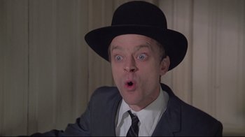 Movie still from “Wise Blood” (1979), directed by John Huston – A person wearing a suit and a black hat; Close Up shot, Low angle