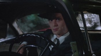 Movie still from “Wise Blood” (1979), directed by John Huston – A man in a suit and tie sitting in the driver's seat of a car; Close Up shot, Low angle
