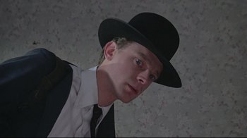 Movie still from “Wise Blood” (1979), directed by John Huston – A man wearing a black hat and a white shirt; Close Up shot, Low angle