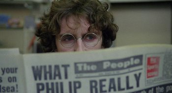 Movie still from “Withnail & I” (1987), directed by Bruce Robinson – A person with glasses reading a newspaper; Close Up shot, Over the shoulder angle