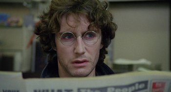 Movie still from “Withnail & I” (1987), directed by Bruce Robinson – A man with glasses is reading a newspaper; Close Up shot, Over the shoulder angle