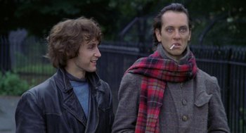 Movie still from “Withnail & I” (1987), directed by Bruce Robinson – Two men standing next to each other and one has a cigarette in his mouth; Medium shot, Low angle