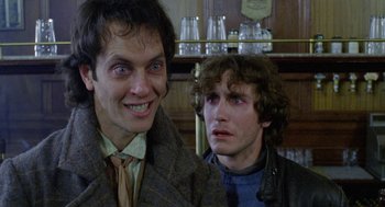 Movie still from “Withnail & I” (1987), directed by Bruce Robinson – Two men are standing next to each other in a bar; Close Up shot, Low angle