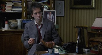 Movie still from “Withnail & I” (1987), directed by Bruce Robinson – A man sitting at a table smoking a cigarette; Medium shot, Low angle