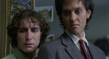 Movie still from “Withnail & I” (1987), directed by Bruce Robinson – Two men standing next to each other in a room; Close Up shot, Low angle