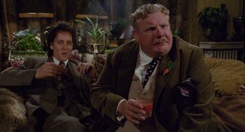 Movie still from “Withnail & I” (1987), directed by Bruce Robinson – Two men sitting at a table with a drink in front of them; Medium shot, Over the shoulder angle